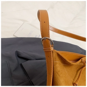 Détail de la bandoulière réglable et boucle argentée sur le sac cabas en daim marron