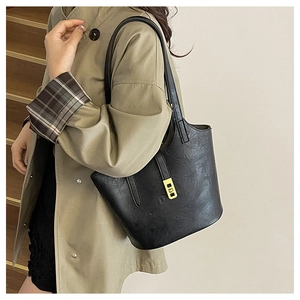 Detail of black tote bag with gold metal buckle and vintage pleated leather texture
