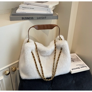 Detail view of a plush white faux fur handbag with leather handle and gold chain strap
