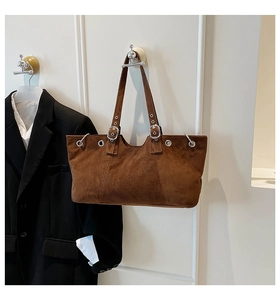 Detail showing the dark brown suede texture and silver metal eyelets of the tote bag