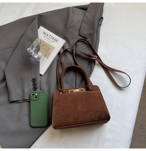 Detailed view of dark brown suede bag featuring a gold metal square buckle and handle