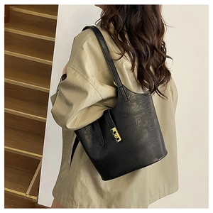 Side view of a black vintage oil wax leather tote bag with gold lock buckle on a model