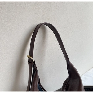 Detail of adjustable chocolate leather shoulder strap with refined gold buckle hardware
