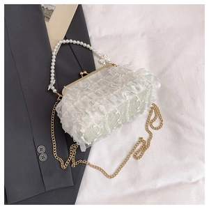 Détail du sac de soirée en dentelle à volants avec anse en perles et chaîne dorée