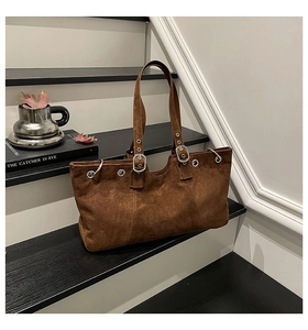 Detail view of large brown suede tote with silver metal eyelets and adjustable buckles