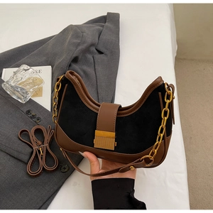 Close-up of crescent underarm bag in black suede and brown leather with gold chain