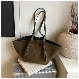 Detail of olive green suede tote bag with long straps on a metallic suitcase