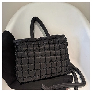 Détail du sac cabas matelassé noir avec texture brillante sur une chaise minimaliste