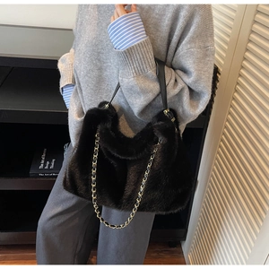 Detail of black faux fur shoulder bag featuring golden metal chain and leather handle texture