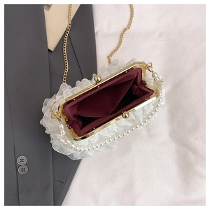 Détail du sac en dentelle blanche avec poignée en perles et chaîne dorée