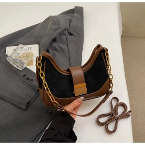 Close-up of retro black suede and brown leather underarm bag with gold metal chain
