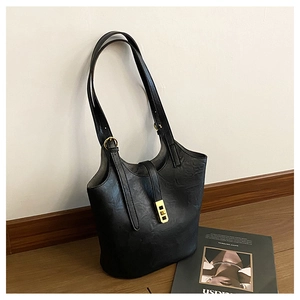 Detail of black faux leather tote bag with vintage texture and gold magnetic clasp
