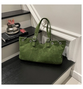 Detail view of moss green suede tote bag with silver metal eyelets and adjustable buckle strap