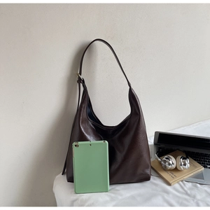 Detail view of large brown faux leather hobo bag showing size comparison with a tablet