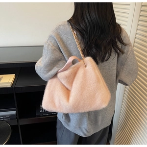 Chic light pink plush shoulder bag with gold-tone chain strap shown in a lifestyle setting