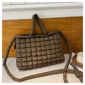 Détail du sac fourre-tout matelassé marron avec poignées cylindriques et sangle