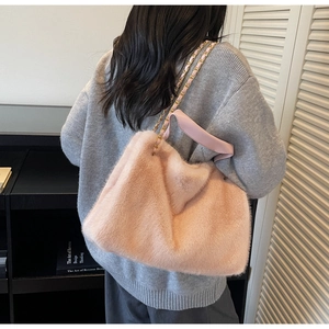 Detailed view of pink plush shoulder bag with golden chain strap on a model