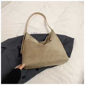 Détail du sac hobo en daim kaki avec coutures distinctives sur une surface en tissu de qualité