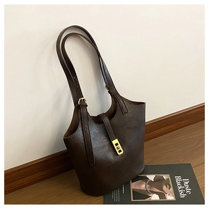 Detail of dark brown leather tote bag with natural texture and elegant gold metal clasp