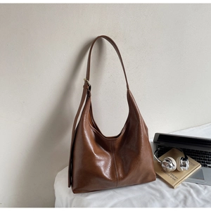 Close-up of the adjustable strap and gold buckle on a brown leather hobo shoulder bag
