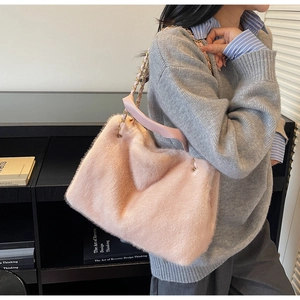 Detail of pink faux fur shoulder bag with soft plush texture and golden chain strap