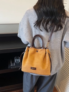 Sac seau en daim jaune avec cordon en cuir et poignée, porté par un mannequin femme