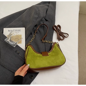 Detalle de bolso hobo de ante verde con ribete de cuero marrón y cadena de metal dorado