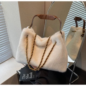 Close-up of white faux fur handbag with brown leather handle and gold chain detail