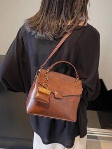 Retro brown leather crossbody bag with top handle and mini charm, 2025 winter style