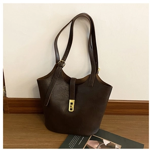 Detailed view of dark brown faux leather tote featuring a golden buckle and textured finish