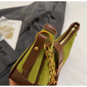 Detail of retro olive green suede handbag with brown leather trim and gold metal chain