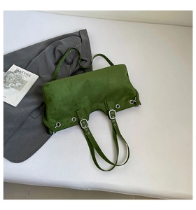 Close-up of grass green suede shoulder bag with silver eyelets and buckle details