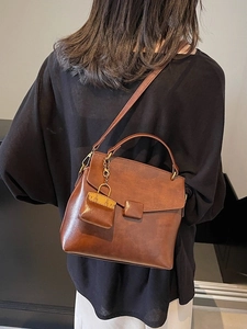 Retro brown leather crossbody bag for women with a mini charm on a black outfit