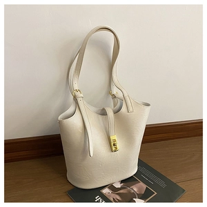 Detailed macro view of cream leather bucket bag with elegant golden rectangular clasp