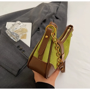 Detail of avocado green suede and brown leather contrast stitching with gold chain