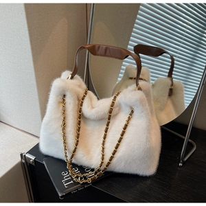 Detail of white faux fur handbag featuring brown leather handles and gold metal chain