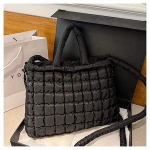Détail d'un sac bouffant matelassé noir avec texture et bandoulière dans une boîte cadeau