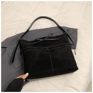 Détail du sac bandoulière noir mat avec surpiqûres blanches et nœud décoratif élégant