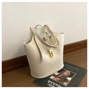 Detailed close-up of cream leather tote bag with glossy texture and golden metal lock