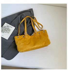 Macro detail of yellow suede tote bag featuring silver metal eyelets and adjustable straps