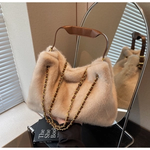 Detail of soft beige faux fur tote bag with brown leather handle and gold chain strap