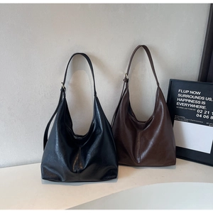 Detail of minimalist hobo bags in black and brown faux leather with gold buckles
