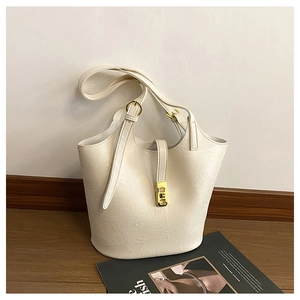 Close-up of cream leather tote bag with gold buckle and smooth pebble grain texture