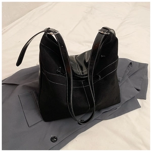 Détail du sac cabas en daim noir avec coutures blanches contrastées et boucle argentée