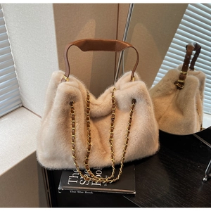Close-up of beige faux fur handbag featuring brown leather handle and gold chain strap