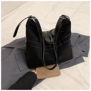 Détail du grand sac cabas noir avec surpiqûres blanches et smartphone pour l'échelle de taille