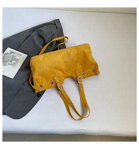 Retro mustard yellow suede tote bag with eyelet details and adjustable straps on grey suit