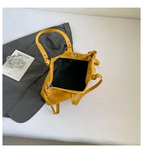 Detailed top view of bright yellow suede tote bag with metallic rivet shoulder straps