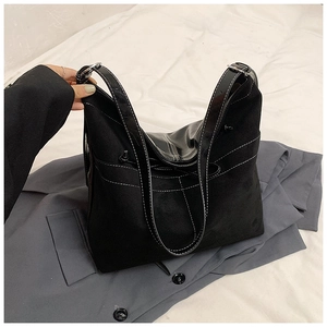 Détail d'un sac cabas noir avec surpiqûres contrastées sur un blazer gris chic