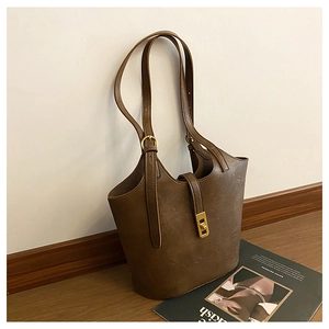 Detail of vintage brown tote bag showing the PU leather texture and gold turn-lock closure